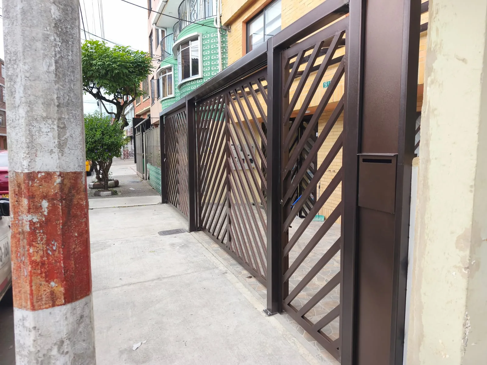 Portón metálico de diseño diagonal instalado en una fachada